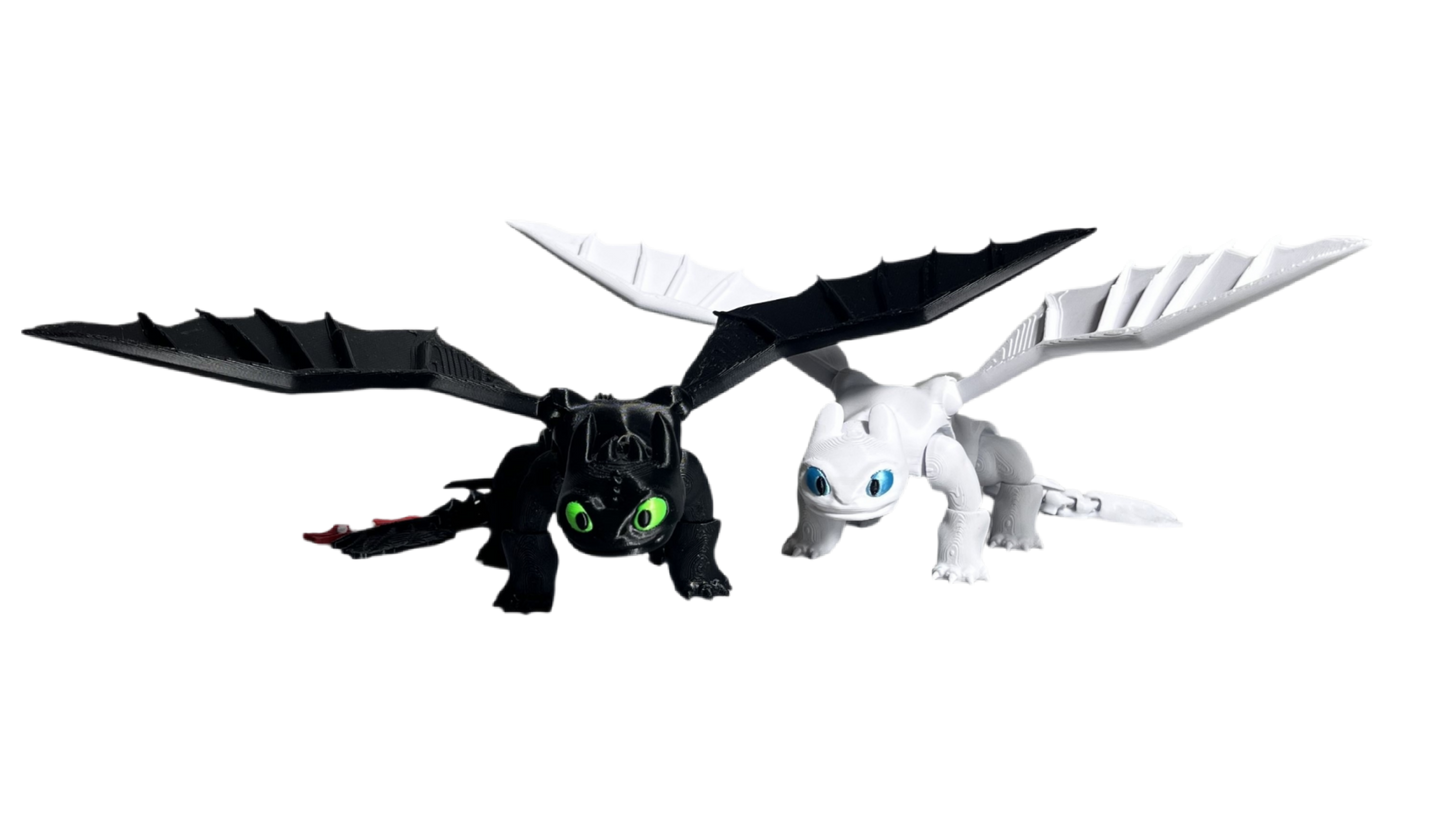 Two toy dragons, one black with green eyes and the other white with blue eyes, on a white background.