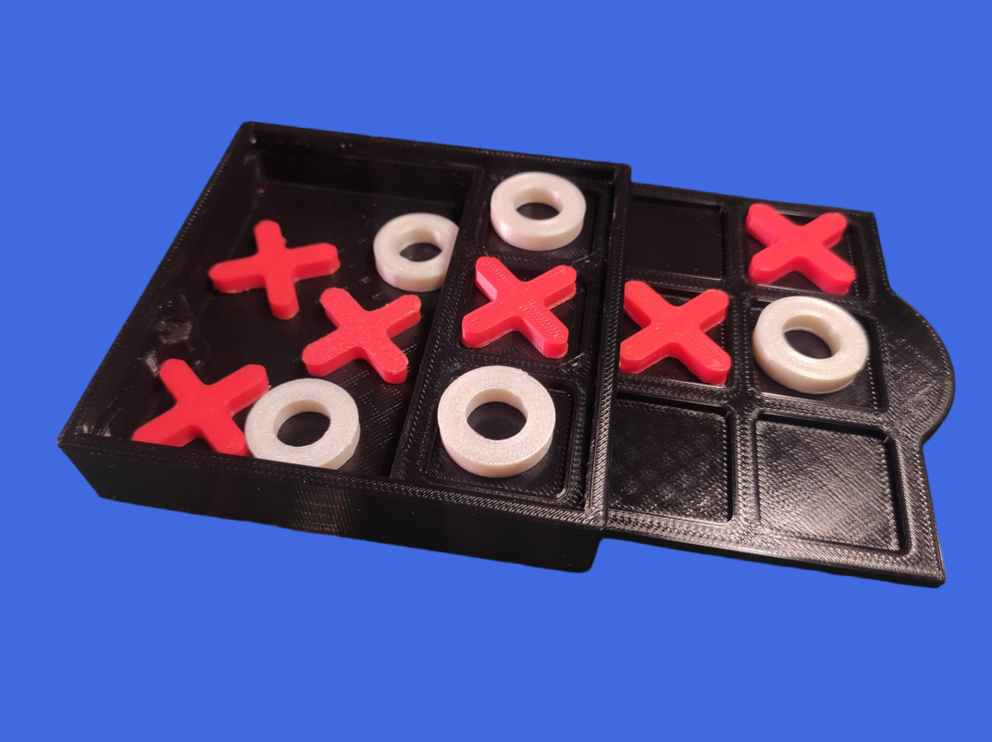 Tic-tac-toe game set with red 'X' and white 'O' pieces on a black board against a blue background.