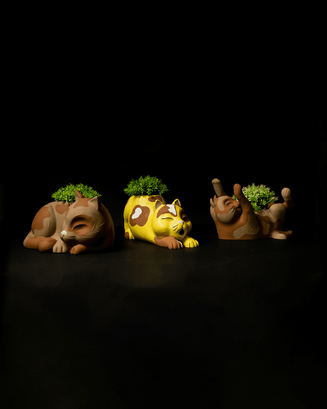 Three animal figurines with plants on a black background