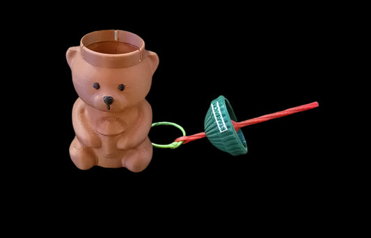 Wooden bear-shaped container with a green and red lid on a black background