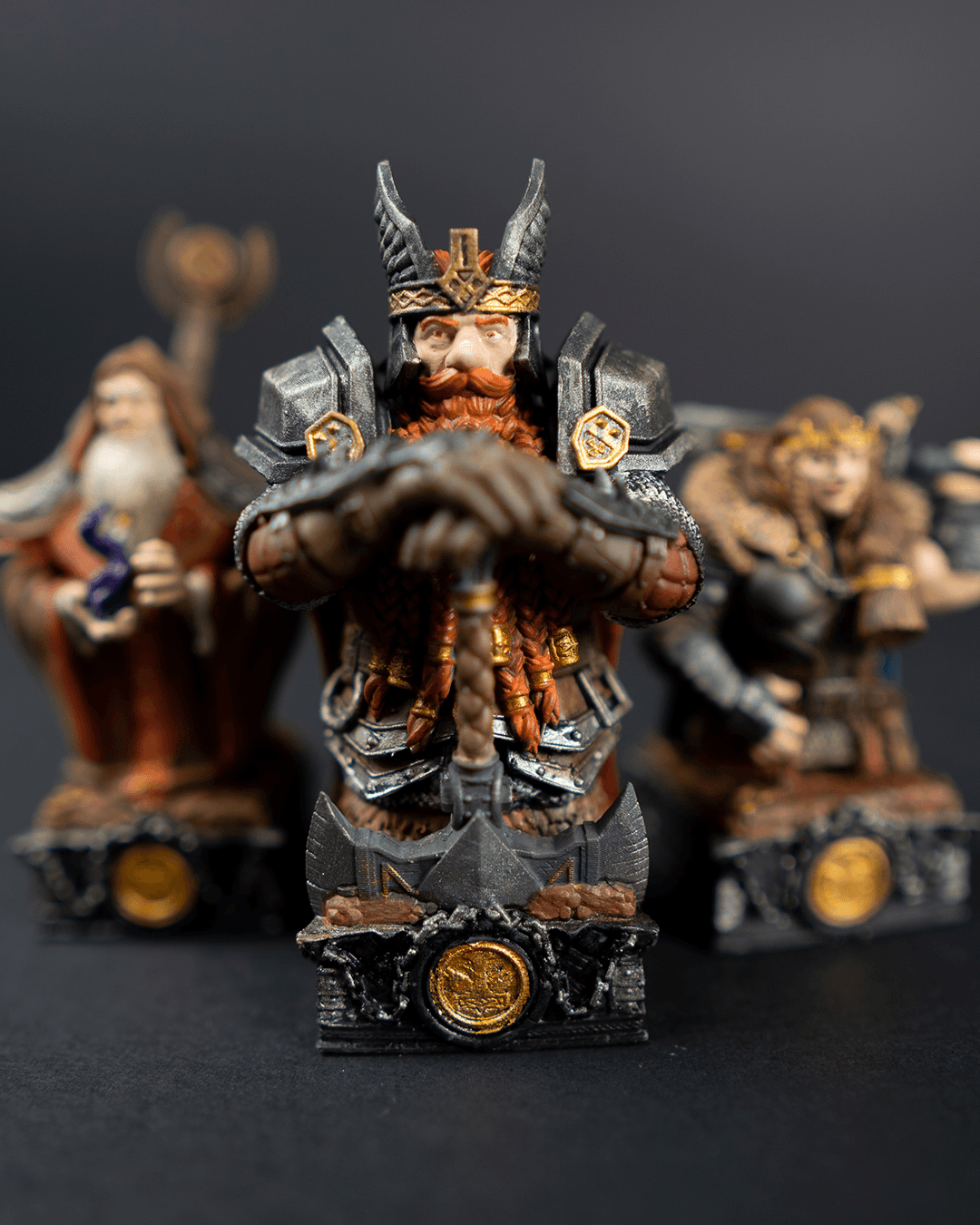 Detailed figurine of a bearded warrior with armor and helmet, standing in front of two other figures on a dark background.