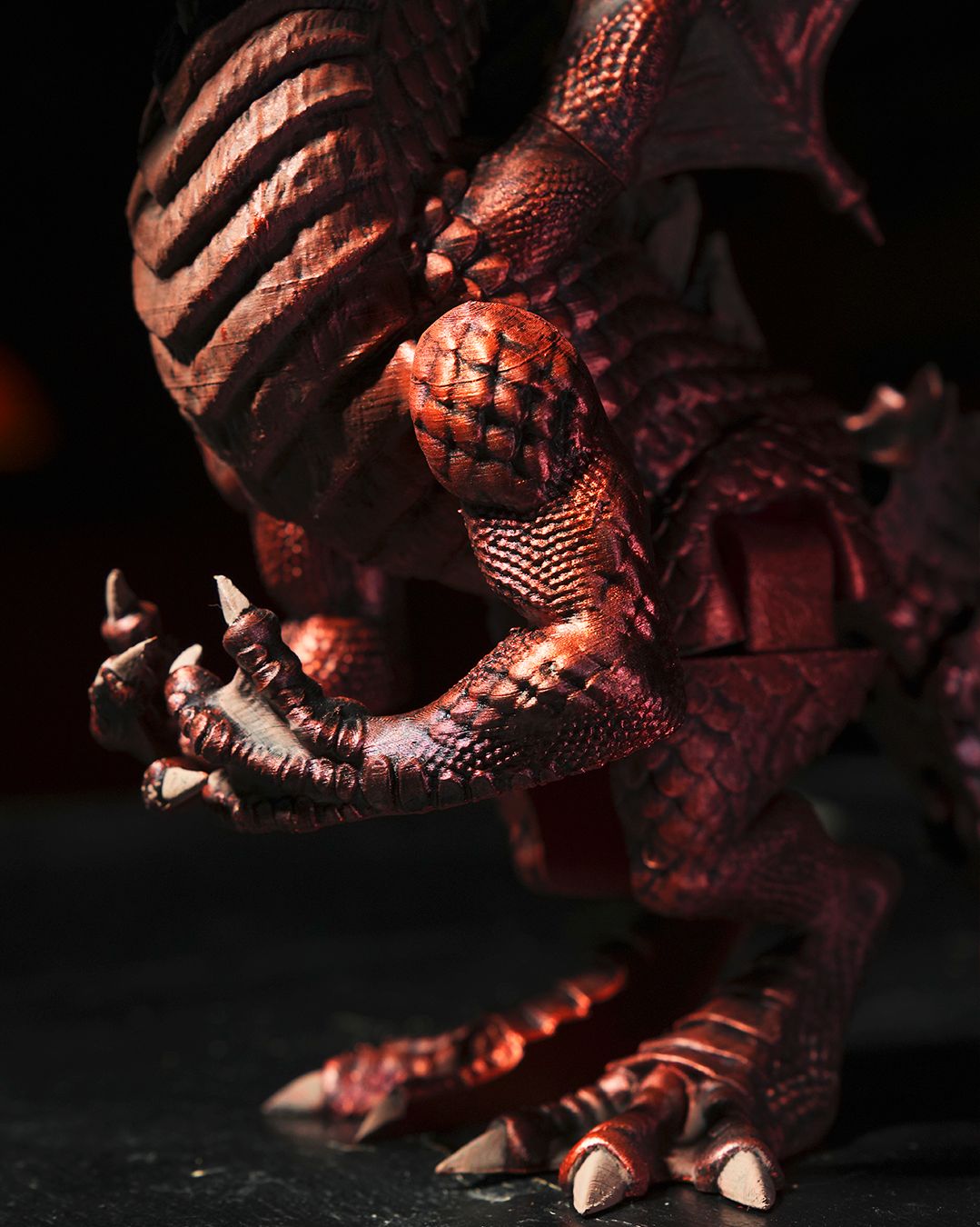 Close-up of a detailed creature model with textured skin and sharp claws on a dark background