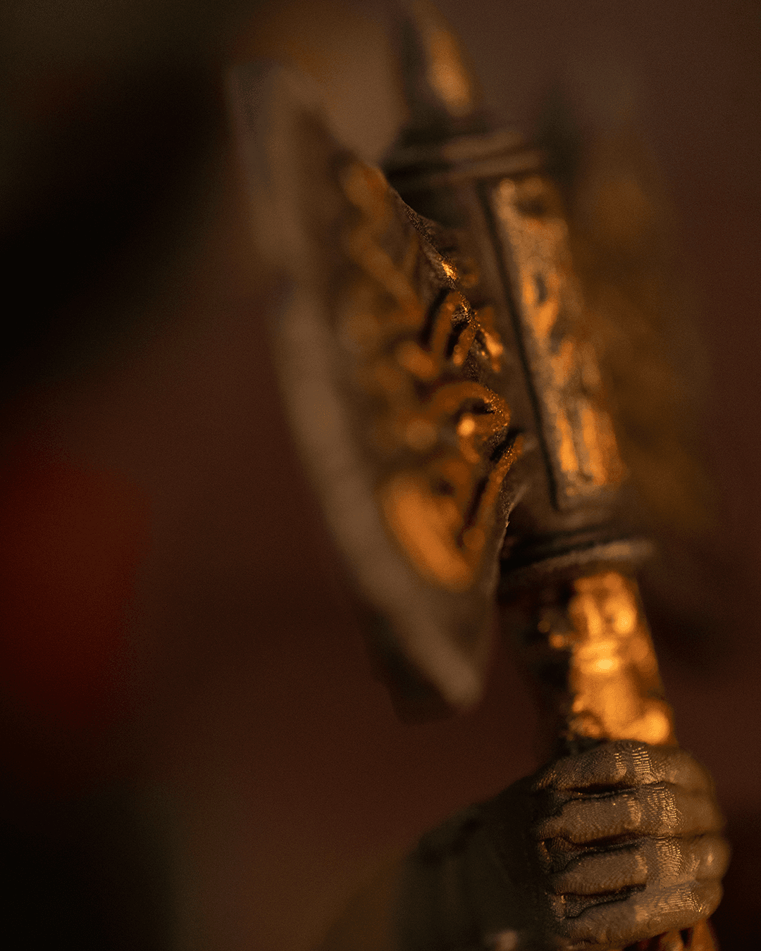 Close-up of a metallic axe with engraved text on a dark background