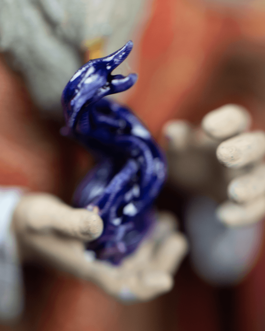 Close-up of a hand holding a small purple figurine against a blurred background