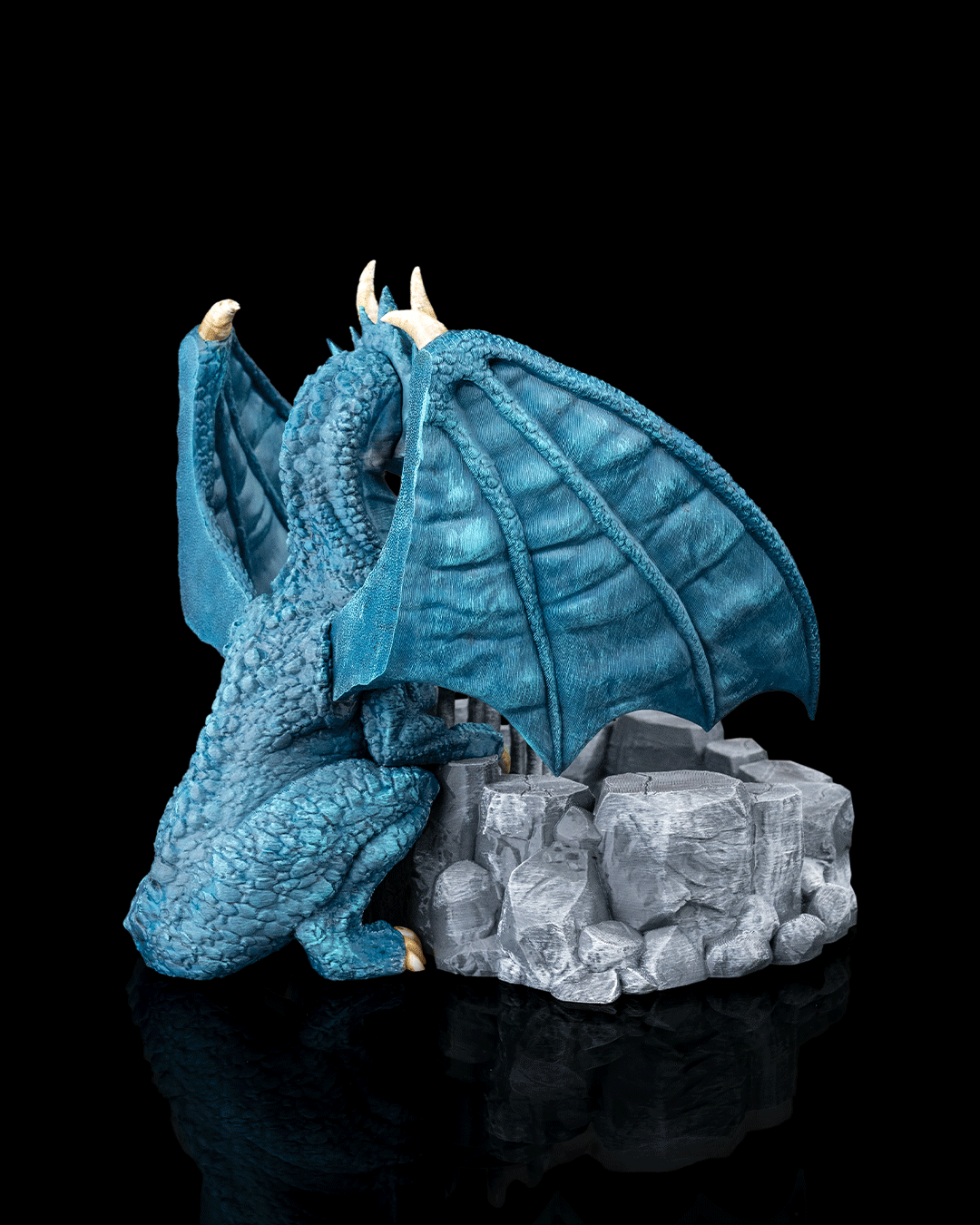 Blue dragon figurine on a rocky base against a black background