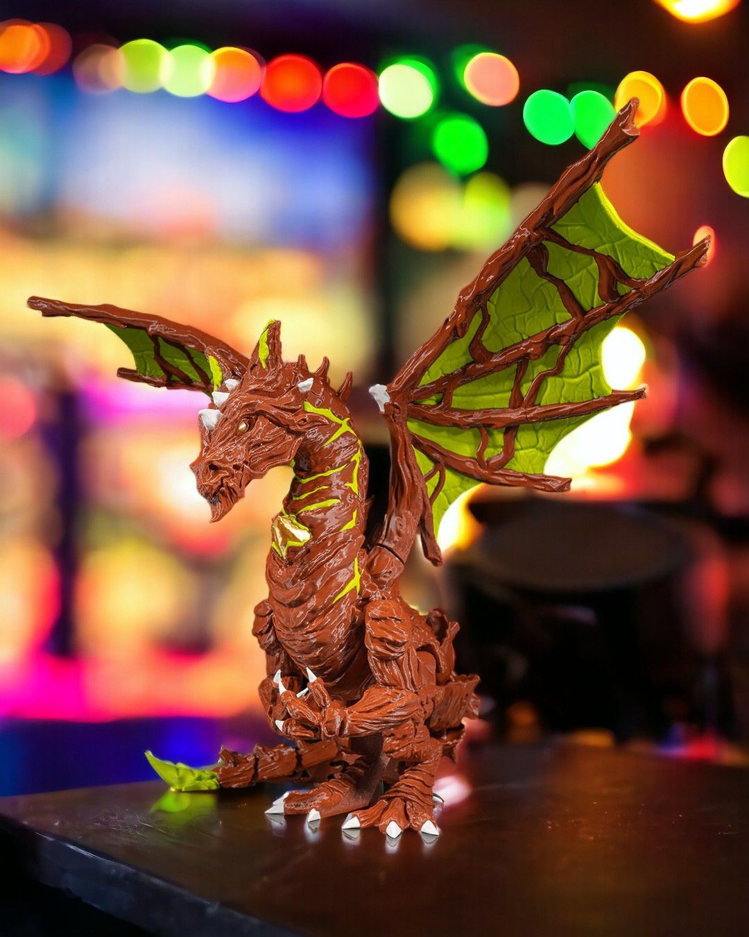 Moss Dragon figurine with glowing green accents on a blurred colorful background