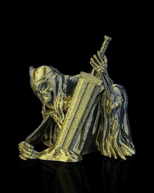 Metallic figurine of a hooded figure holding a staff on a black background