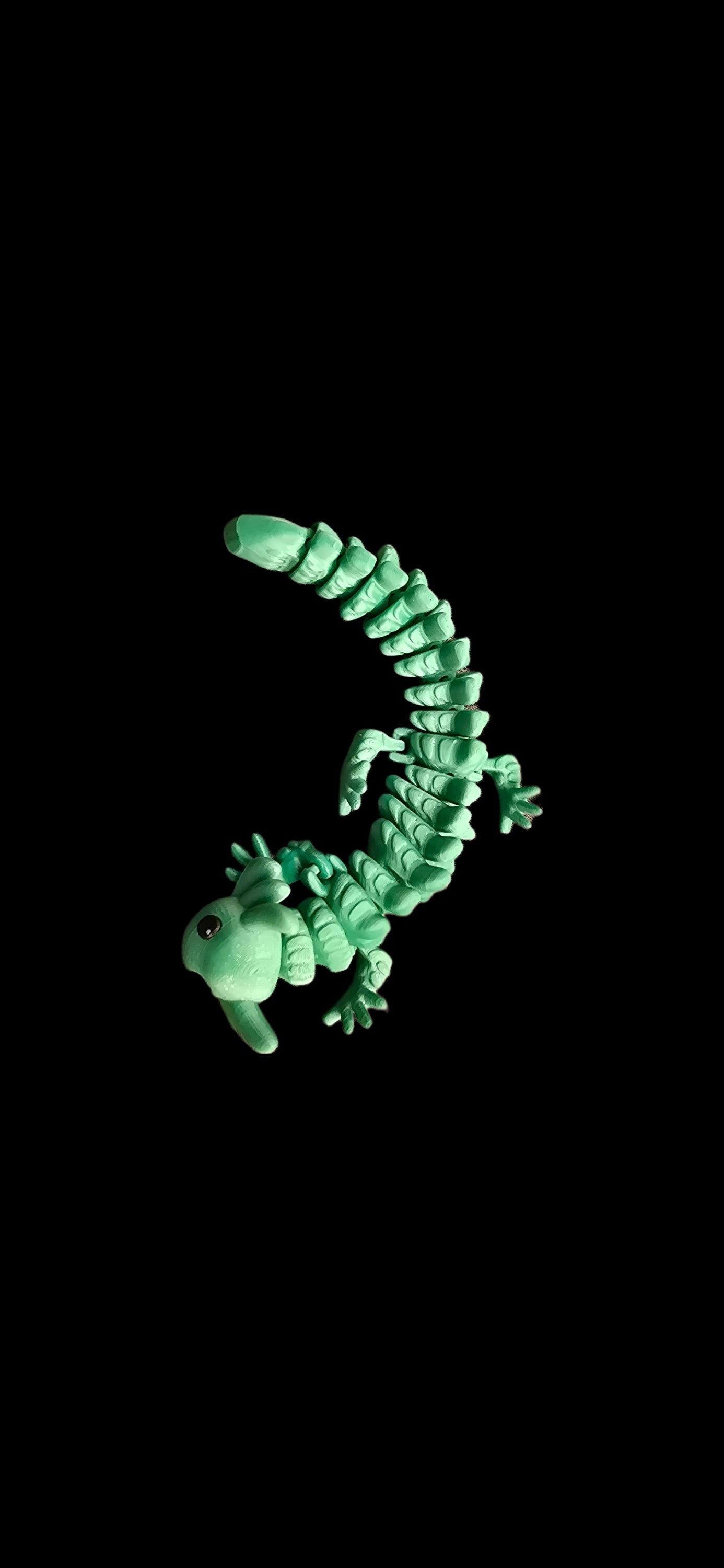 3D printed articulated v2 axolotl figurine in pastel pink PLA+, detailed gills and limbs, flexible body, proudly made locally in Ottawa, displayed on a light wooden surface.