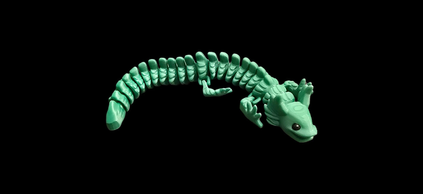 3D printed articulated v3 axolotl figurine in pastel pink PLA+, detailed gills and limbs, flexible body, proudly made locally in Ottawa, displayed on a light wooden surface.