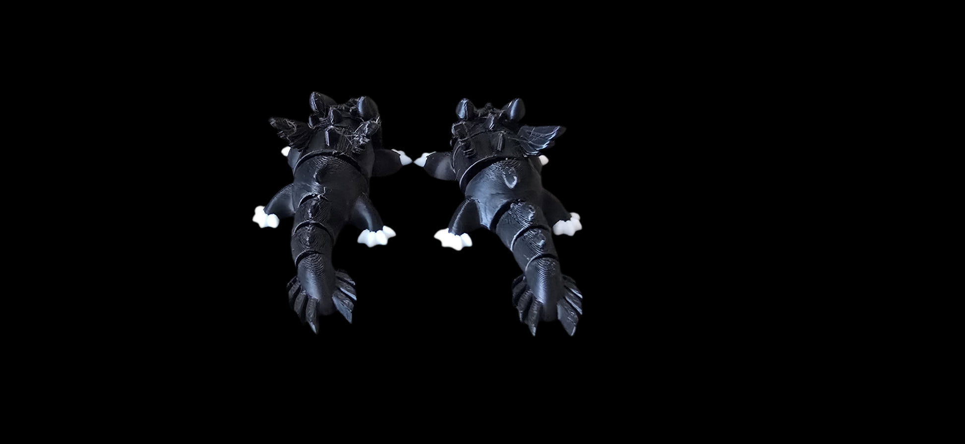 Pair of black dragon-like shoes on a black background